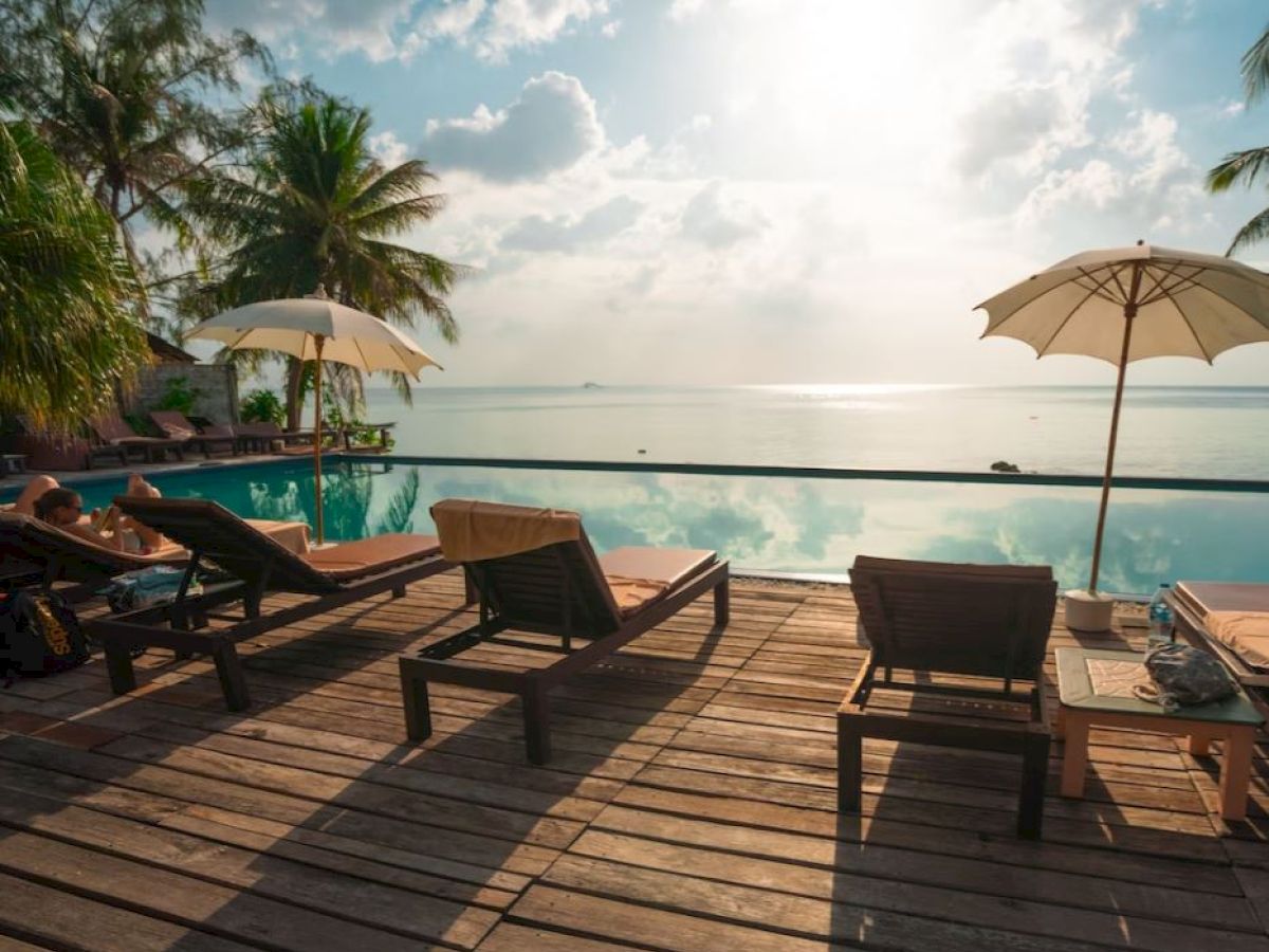 A serene beach scene with lounge chairs, umbrellas, and a calm ocean view under a partly cloudy sky.