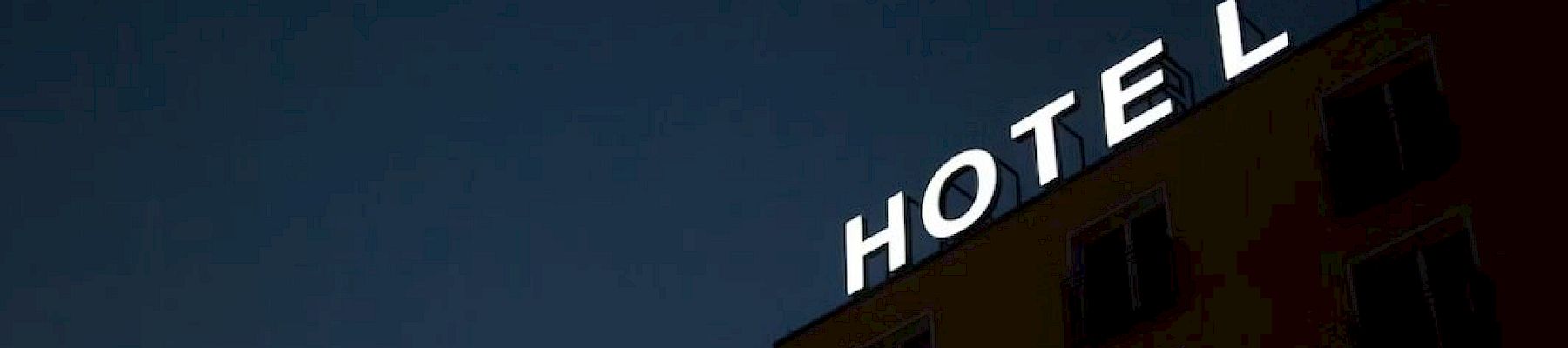 A building with "HOTEL" in bright letters at the top against a dark, night sky.