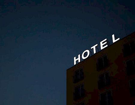 A building with "HOTEL" in bright letters at the top against a dark, night sky.