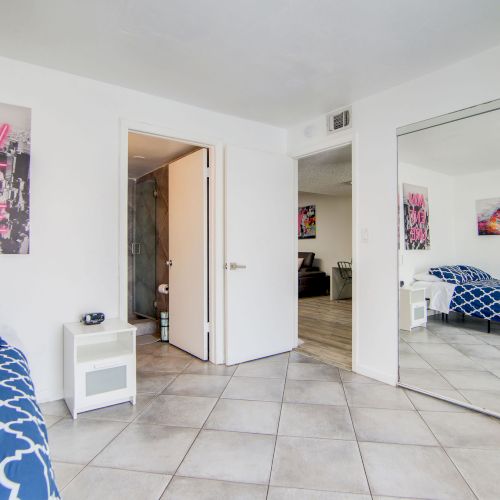 A bedroom with a bed, mirrored closet, artwork, and tile floor is shown. The word "Adventure" appears on a wall decoration.